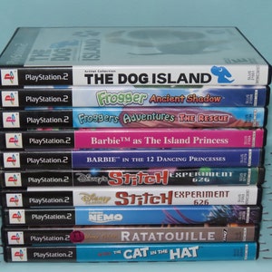 May include: A stack of 10 PlayStation 2 video game cases. The games are: The Dog Island, Frogger Ancient Shadow, Frogger's Adventures The Rescue, Barbie as The Island Princess, Barbie in the 12 Dancing Princesses, Disney's Stitch Experiment 626, Disney's Stitch Experiment 626, Finding Nemo, Ratatouille, and The Cat in the Hat.