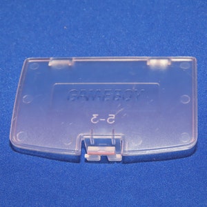 May include: A clear plastic Game Boy Color game cartridge case with the text "GAME BOY" and "C-2" printed on it.