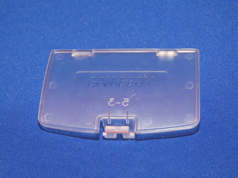 May include: A clear plastic Game Boy Color game cartridge case with the text "GAME BOY" and "C-2" printed on it.