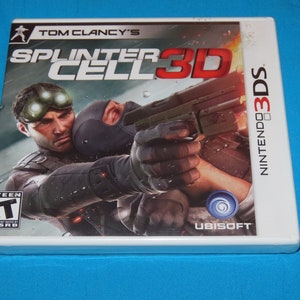 May include: A white Nintendo 3DS game case with a black and green image of a man holding a gun. The game is called "Splinter Cell 3D" and is a Tom Clancy's game. The ESRB rating is Teen.