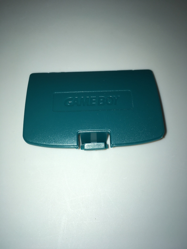 May include: A teal green Game Boy Color game cartridge case with the word "GAME BOY" embossed on the front.