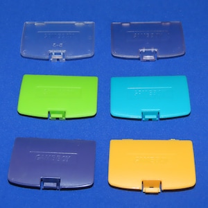 May include: Six Nintendo 64 game cartridge cases in different colours: clear, green, blue, purple, yellow, and light blue. Each case has the Nintendo 64 logo printed on it.
