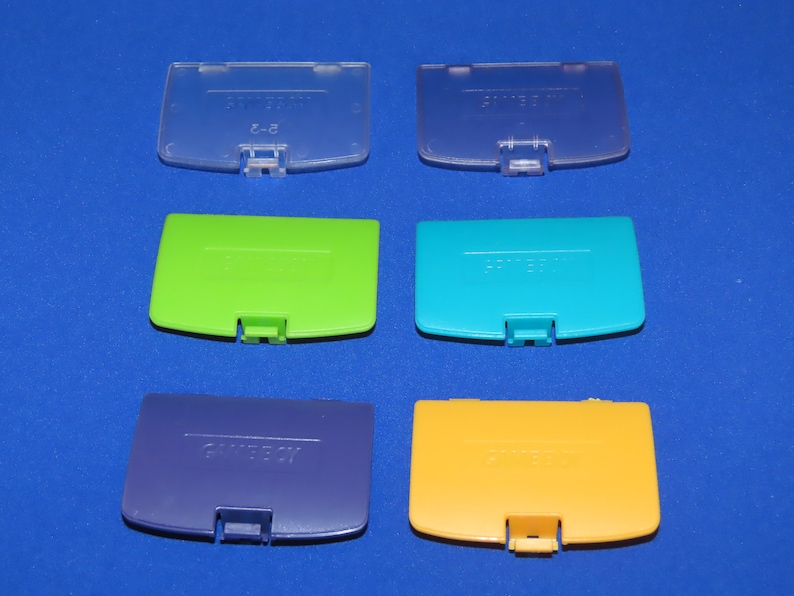 May include: Six Nintendo 64 game cartridge cases in different colours: clear, green, blue, purple, yellow, and light blue. Each case has the Nintendo 64 logo printed on it.