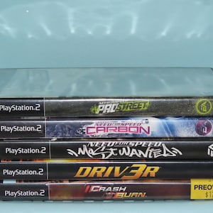 May include: A stack of five PlayStation 2 video game cases. The games are Need for Speed ProStreet, Need for Speed Carbon, Need for Speed Most Wanted, Driver 3, and Crash:  Burn. The cases are black with a PlayStation 2 logo on the spine. The games are all racing games.