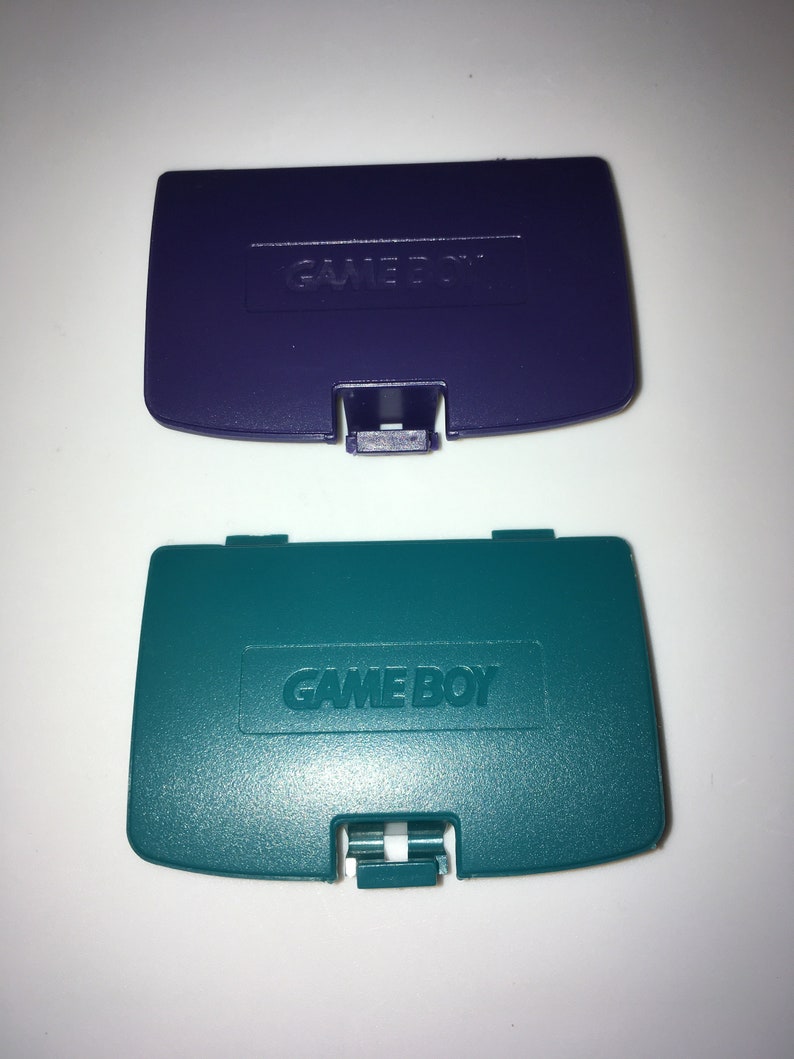May include: Two Game Boy Color game cartridge covers. One is purple and the other is teal.