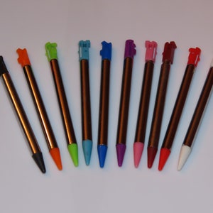 May include: A set of ten stylus pens with different colored tips. The tips are black, orange, green, light blue, dark blue, purple, pink, red, red, and white.