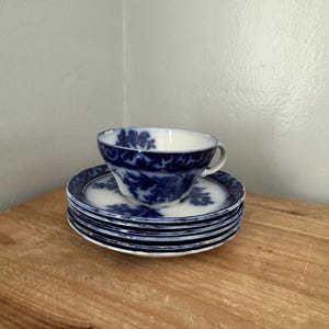 Puede incluir: Un juego de tazas y platillos de té de porcelana azul y blanca con un patrón floral. Las tazas y los platillos están apilados uno encima del otro.