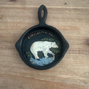 May include: Black cast iron skillet-shaped decorative item with a white polar bear image and the text "WASHINGTON ZOO". The bear is depicted on a blue and green background.