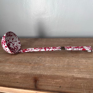 Rode emaille pollepel met spatwater