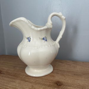 Antique ceramic pitcher with blue floral design and decorative handle