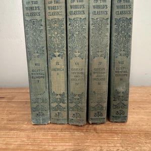 May include: A collection of five antique books titled "The Best of the World's Classics." The books have light blue covers with ornate floral designs and text. The spines display the title and volume numbers, including "America" and "Continental Europe."