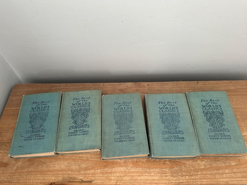 May include: Five vintage books titled "The Best of the World's Classics" are displayed on a wooden surface. The books have a teal cover with ornate text and design. The text includes the editor's name, Henry Cabot Lodge.