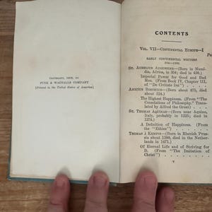 May include: Open book with the title "CONTENTS" and a list of early continental writers. The book is open to a page with text, including "St. Aurelius Augustine" and "St. Thomas Aquinas". The book is printed by Funk & Wagnalls Company.