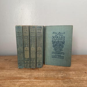 May include: A collection of vintage books titled "The Best of the World's Classics." The books are bound in a faded teal color with ornate embossed designs and text. The spines display volume numbers and titles. The book on the right is standing upright.