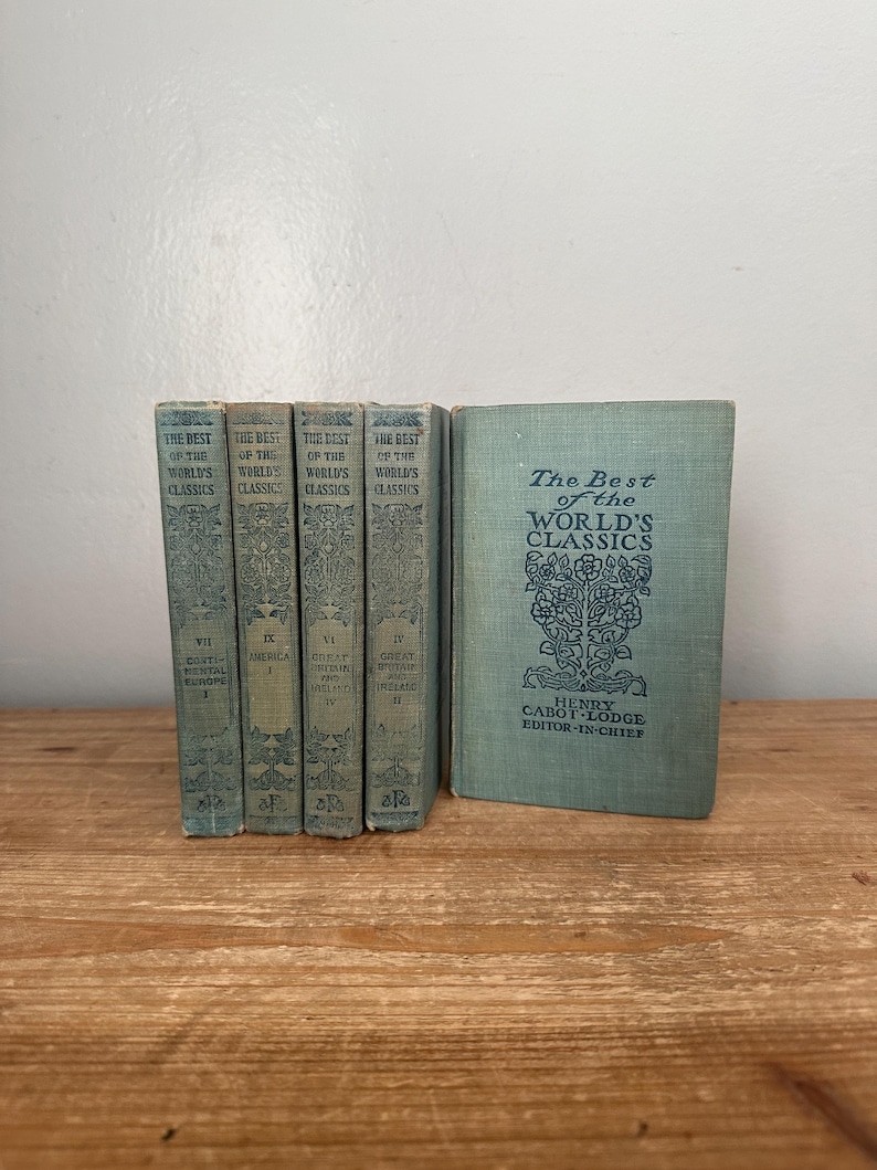 May include: A collection of vintage books titled "The Best of the World's Classics." The books are bound in a faded teal color with ornate embossed designs and text. The spines display volume numbers and titles. The book on the right is standing upright.