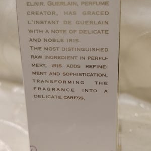 May include: A white perfume box with text describing a luminous winter fragrance. The text includes phrases like "Christmas Scent," "delicate caress," and "noble iris." The box is a limited edition natural spray.