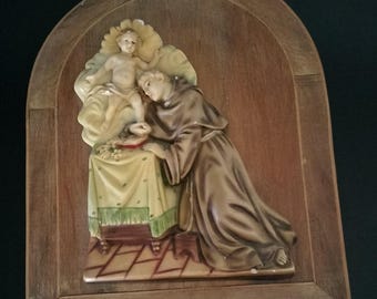 Vintage sacred painting of Saint Anthony with child on wood, wooden bedside with resin bas-relief of Saint Anthony