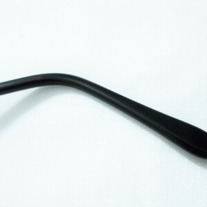 May include: Black plastic temple arm of a pair of eyeglasses.