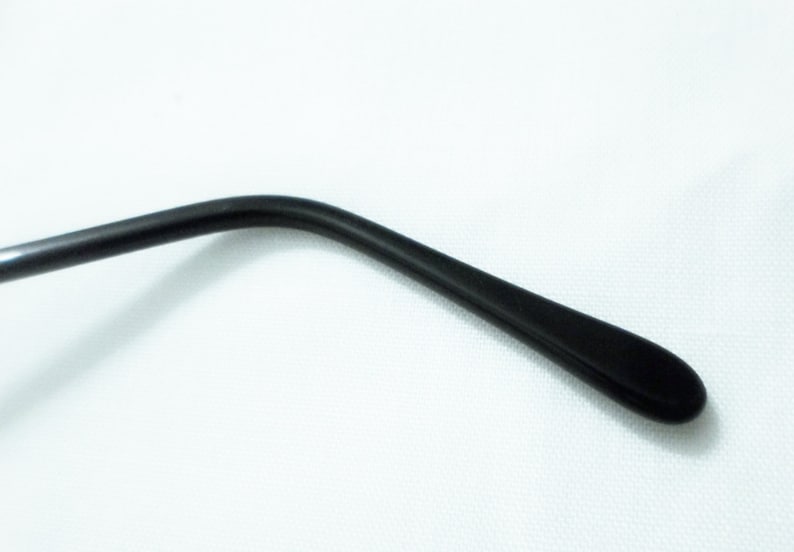 May include: Black plastic temple arm of a pair of eyeglasses.