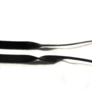 May include: Two black rubber straps with a wavy design. The straps are for glasses or sunglasses.