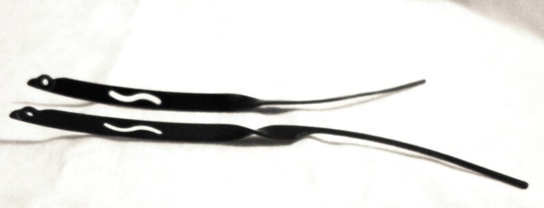 May include: Two black rubber straps with a wavy design. The straps are for glasses or sunglasses.