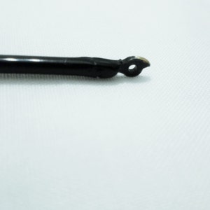 May include: A black, thin, flexible rod with a small, rounded, metal tip.