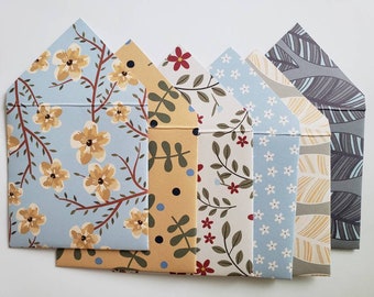 May include: Set of six decorative envelopes with different floral and geometric patterns. The envelopes are in shades of blue, yellow, gray, and red.