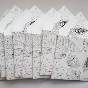 May include: A set of eight white envelopes with black ink illustrations of seashells, starfish, and other ocean-themed designs.