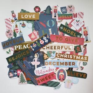 May include: A collection of Christmas themed paper craft embellishments with gold foil accents. The embellishments feature words like "Love", "Jolly", "Noel", "To Give", "Cheerful", "Christmas", "December", "The Nutcracker", "Sweet", and "Believe".