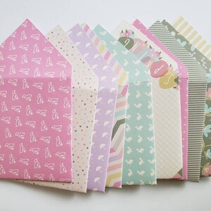 May include: A set of ten colorful envelopes with various patterns, including birds, polka dots, and stripes. The envelopes are all folded and stacked on top of each other.