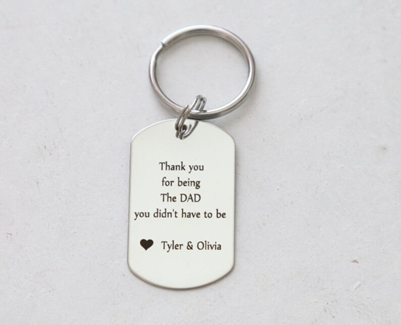 May include: Silver keychain with a tag that reads "Thank you for being The DAD you didn't have to be" with a heart and the names Tyler & Olivia.