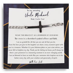 Könnte beinhalten: Ein silbernes Armband mit einem Kreuzanhänger. Die Karte lautet "An meinen großartigen Onkel Michael Bester. Onkel. Immer." und enthält eine Botschaft darüber, dass das Armband eine Erinnerung an ihre Verbindung ist. Die Karte sagt auch "Tragen Sie dieses Armband als Erinnerung an unsere Verbindung. Das Kreuz ist ein geschätztes Symbol für Liebe und Glauben. Ich bin so dankbar für alles, was du bist und alles, was du tust. Von der Liebe, die du gibst, bis zum Lachen, das wir teilen, jeder Moment, den wir miteinander verbringen, ist ein Schatz. Ob es deine lustigen Witze oder deine weisen Ratschläge sind, du bringst meinen Tag immer zum Strahlen. Danke, dass du mir sagst, dass du immer da sein wirst - deine Anwesenheit ist eine beruhigende Konstante in einer sich ständig verändernden Welt. Ich bin so dankbar, einen Onkel wie dich zu haben, jemanden, der mich inspiriert, jeden Tag mit deiner Weisheit und Großzügigkeit des Geistes besser zu werden. Mit Liebe, Jack."