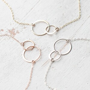 May include: Three delicate necklaces with interlocking circle pendants. The necklaces are made of gold, rose gold, and silver chain.
