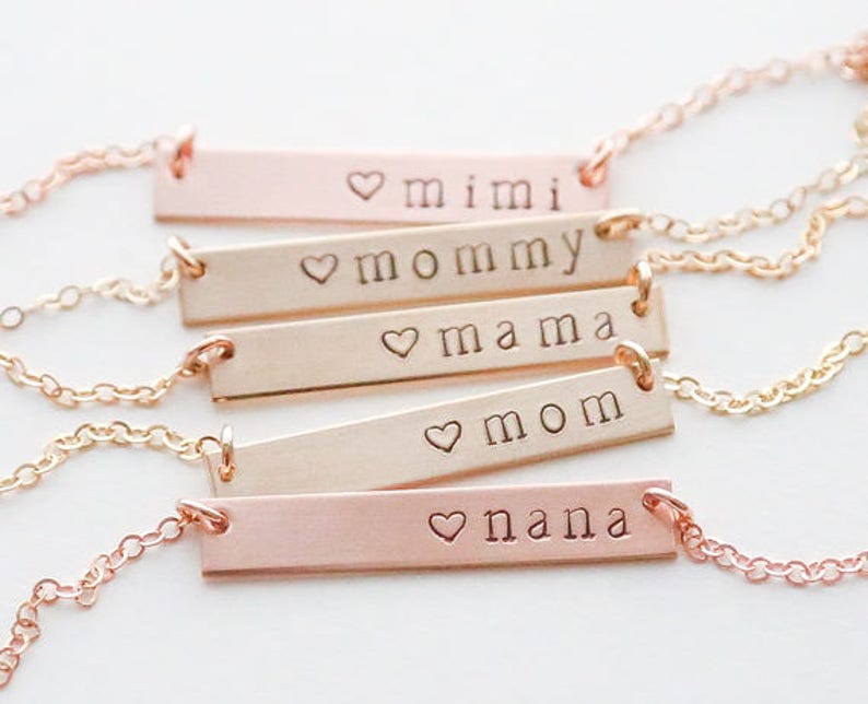 May include: Five gold and rose gold bar necklaces with heart charms and engraved words: mimi, mommy, mama, mom, and nana.