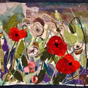 May include: A colorful fabric art piece depicting a field of red poppies with green leaves and stems. The background is a mix of brown, green, and white fabrics.