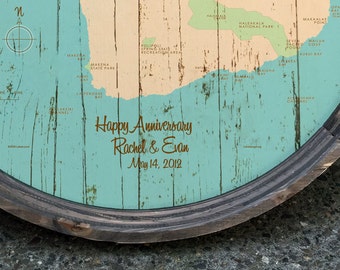 Puede incluir: Un mapa de madera redondo de una isla, con una combinación de colores turquesa y beige. El mapa está enmarcado con un borde de madera oscura. El texto "Happy Anniversary Rachel & Evan May 14, 2012" está escrito en cursiva en el mapa.