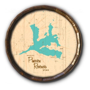 May include: A round wooden sign featuring a map of Pineview Reservoir in Utah, with the lake in turquoise against a beige background. The sign is framed by a dark brown wooden border, and the text "Beautiful Pineview Reservoir Utah" is displayed.