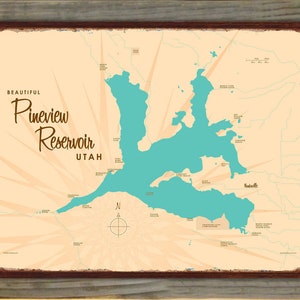 May include: A framed map print of Pineview Reservoir in Utah. The map features a teal-colored reservoir against a beige background, with the words "Beautiful Pineview Reservoir Utah" in a decorative font. The frame is brown.