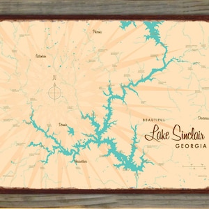 May include: A vintage-style map of Lake Sinclair in Georgia, featuring a light tan background with teal blue water features and radiating lines. The map is framed in a dark brown border and includes the text "BEAUTIFUL Lake Sinclair GEORGIA".