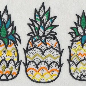 May include: Three embroidered pineapple designs with intricate patterns. Each pineapple features a black outline, with colorful details in teal, green, yellow, and orange. The designs have a tropical theme.
