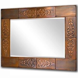May include: A rectangular mirror with a copper-colored frame. The frame is made of tiles with an intricate, embossed design.