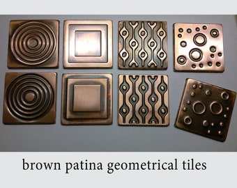 May include: Eight brown patina geometric tiles with different patterns. The tiles are square and have a raised design. The patterns include concentric circles, squares, wavy lines, and circles.
