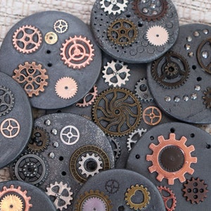 May include: A collection of round, gray, decorative coasters with various sized metal gears and cogs in shades of copper, silver, and bronze.
