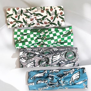 May include: Set of four green, white, and blue patterned headbands with a knot design. The headbands feature a football and eagle design.