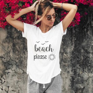May include: White t-shirt with black text that says "beach please" and a sun graphic.