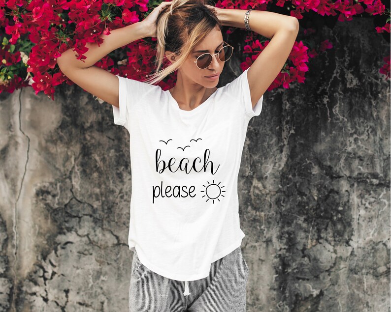 May include: White t-shirt with black text that says "beach please" and a sun graphic.
