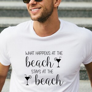 May include: White t-shirt with black text that reads "What happens at the beach stays at the beach" with a cocktail glass graphic.