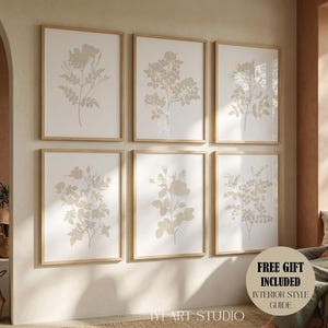 May include: A set of six framed wall art prints featuring beige botanical illustrations of various flowers and leaves on a white background, arranged in two rows of three, with light wood frames and a circular sticker reading FREE GIFT INCLUDED.
