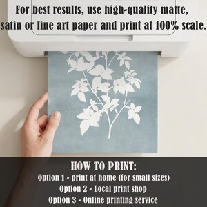 May include: A white printer outputting a square sheet of paper featuring a white botanical leaf silhouette on a dusty blue background. The text reads: For best results, use high-quality matte, satin or fine art paper and print at 100% scale. HOW TO PRINT: Option 1 - print at home (for small sizes) Option 2 - Local print shop Option 3 - Online printing service.