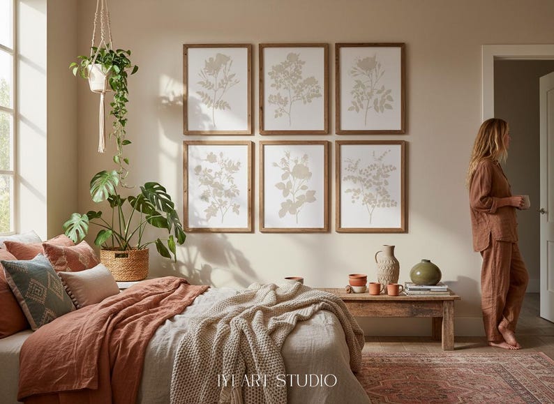 May include: A set of six framed botanical wall art prints featuring beige floral illustrations on white backgrounds, arranged in two rows of three. The prints are displayed above a bed with terracotta bedding and a chunky knit throw blanket.